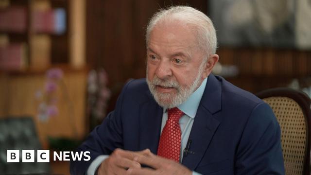 Brazil's President Luiz Inácio Lula da Silva, in a red spotted tie, dark blue suit and light blue shirt, sits in the presidential palace for an interview with the BBC
