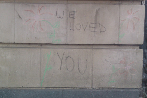 Chalked words on stone wall: "We loved you"