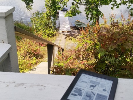 Kindle on ledge overlooking lake with jetty and rowing boat