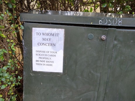 Sign on telecoms equipment cabinet: "To whom it may concern. Dispose of your scratch cards properly. Do not shove them in here."