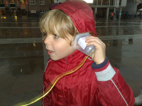 Child listening to yoghurt pot on string