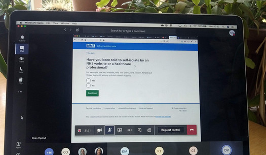 Laptop screen with NHS "Get an isolation note" service displayed on a Microsoft Teams call. 7 callers are shown +46 others
