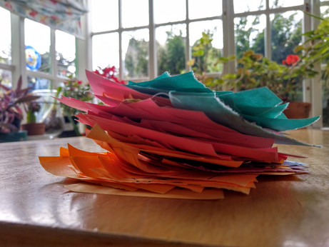 Pile of torn-up sticky notes in  front of houseplants and window
