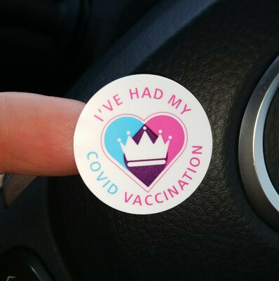 A sticker with a cyan and magenta heart and the words "I've had my COVID vaccination"