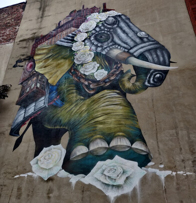 An elephant, surrounded by white roses, with mill buildings on its back.