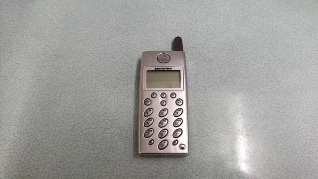 A silver candy bar-style mobile phone with a stubby antenna 