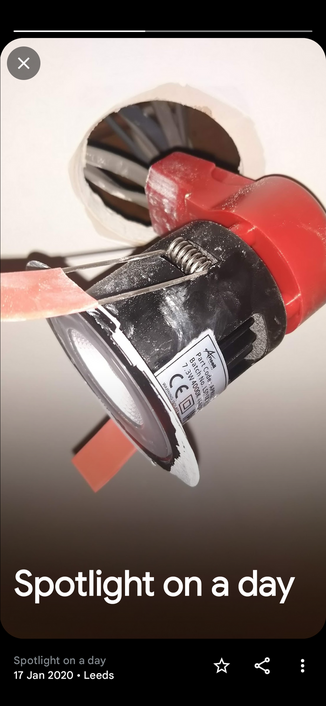 Screenshot from Google Photos showing a picture of a spotlight pulled from the ceiling to reveal its fixing and electrical wires. The auto-generated caption is "Spotlight on a day"