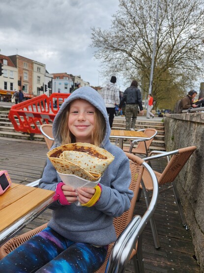 Freya holding a crepe that's bigger than her head, loaded with Nutella and bananas