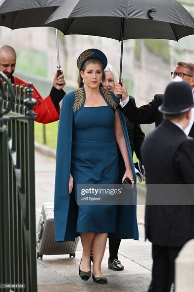 Mordaunt at the coronation in sheer blue dress and cloak with gold, imperial leafing.