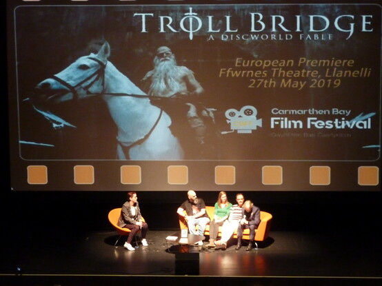 Four members of the creative crew of Troll Bridge being interviewed while sat on the theatre stage.