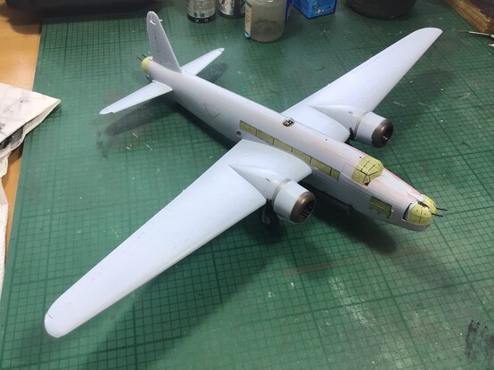 A 1/72nd scale Vickers Wellington bomber. It is unpainted, pale grey plastic, and the windows have been masked with yellow tape ready for painting to begin. The plane has long tapering wings, and a pair of engines. The fuselage is somewhat rounded in cross section. Part of my obsession with military aviation in 1940. 