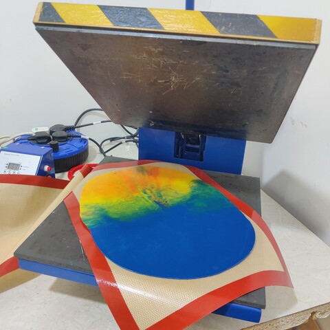 Coloured HDPE plastic melted together to form a sheet, on a silicone baking sheet in a heat press