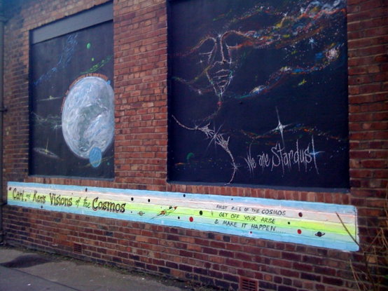 Mural on a brick wall of a space scene.  Underneath is the caption "Carl and Ken's Visions of the Cosmos.  First rule of the cosmos: get off your arse and make it happen..."