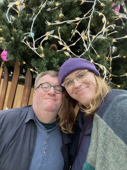 Photo of Jae and James in front of a Christmas tree