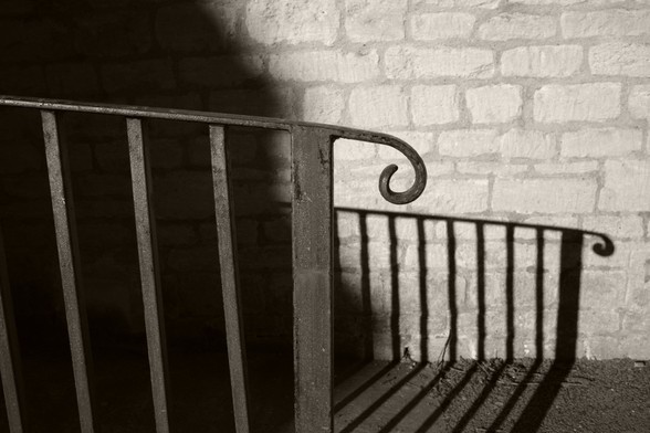 Semi-abstract shot of some metal railings, and the shadow they cast on the stone wall behind them