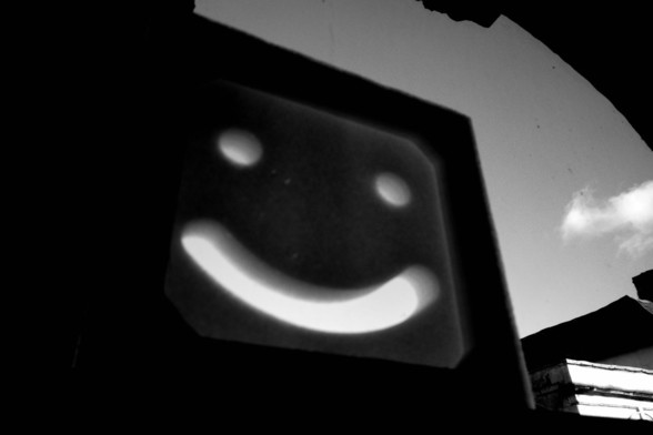 a weird smiley face made of polystyrene sits in a window, smiling at the sky
