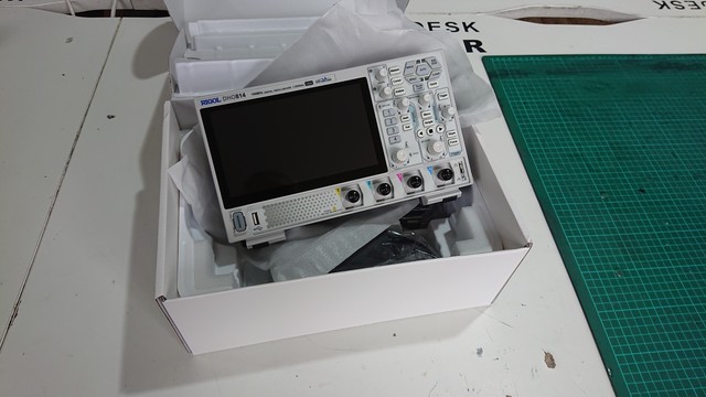 A brand new Rigol DHO814 oscilloscope resting in its box on a workbench 
