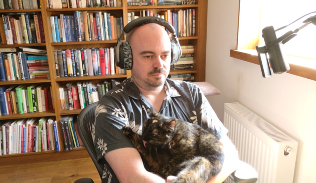 40 something dude in front of his computer being a cat rest for a small tortie