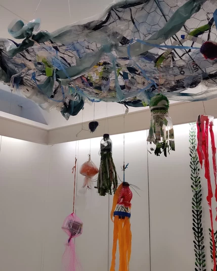 Small jellies made by visitors to the Convenience Gallery "The Town is the Gallery" exhibition, attached to a wavy plastic and netting plane representing the surface of the sea