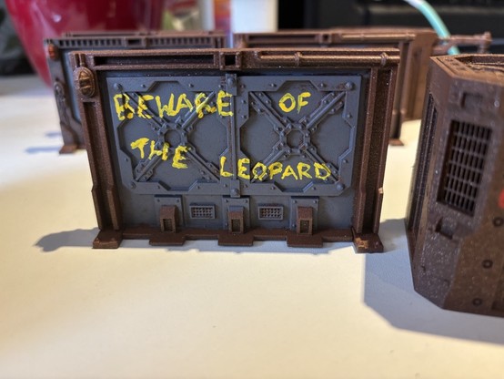 Graffiti painted on a model of an industrial door for wargaming, reading “beware of the leopard”