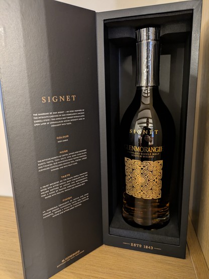 Bottle of Glenmorangie 'Signet' whisky in a presentation wood box. Printed on the inside of the box lid are copious tasting notes (description, colour, nose and taste). 