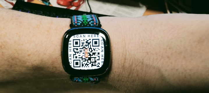 a photo of my wrist with my Fitbit watch on. The watch face is showing a QR code.