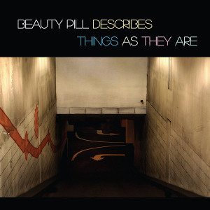 The cover of the Beauty Pill album “Describes Things As They Are”.

The title is presented in pastel coloured type on a black background above an image of an underground internal space. We are looking down through shabby white walls. Maybe a car park, maybe a stadium. There are arrows on the floor at the bottom of the slope. 