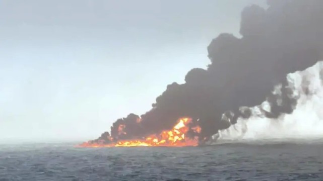 The burning wreckage of the two ships, with flames and black smoke