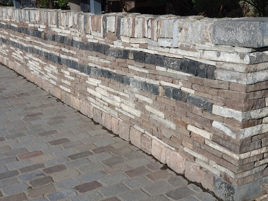 A longer section of the same drywall, made of white and brown stone with two dark stone courses.