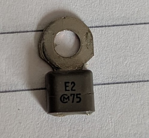 A ring terminal with a grey plastic cuff with E2 and 75 markings and a branding of an m with a c wrapped around it. 