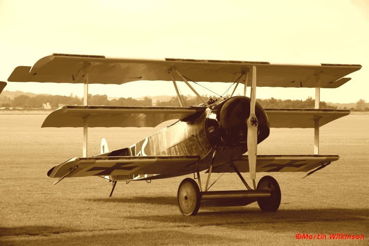 Fokker Dr1 replica on the grass at Duxford. While a generally accurate reproduction this example is powered by a modern engine rather than a 9-cylinder rotary. Fokker Dr1 replica on the grass at Duxford. While a generally accurate reproduction this example is powered by a modern engine rather than a 9-cylinder rotary.