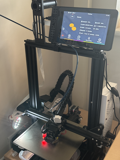 An Ender 3 printer with an LCD touchscreen mounted on the top bar.